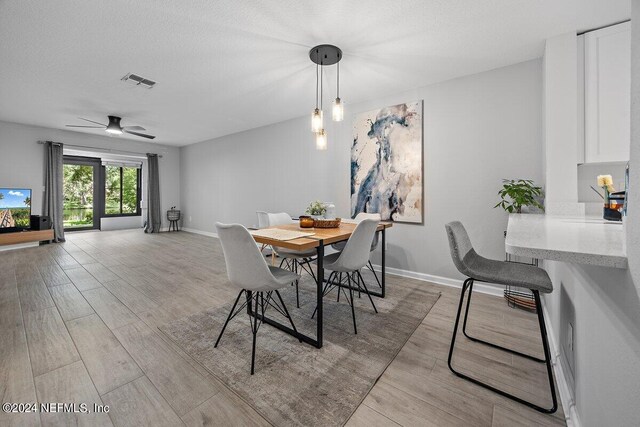 dining space featuring a textured ceiling, ceiling fan, and light hardwood / wood-style flooring