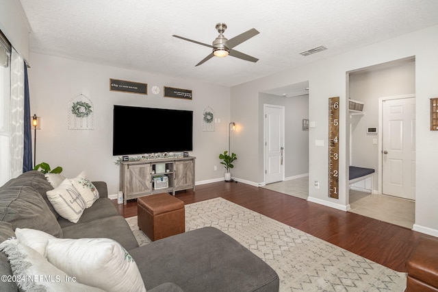 living room with wood-type flooring, a textured ceiling, and ceiling fan