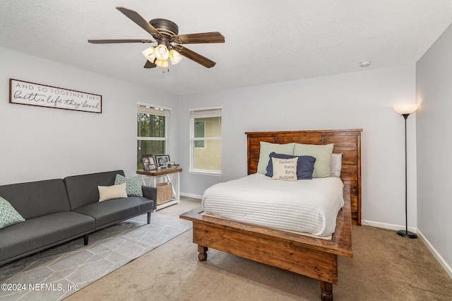 bedroom with ceiling fan, carpet flooring, and a textured ceiling