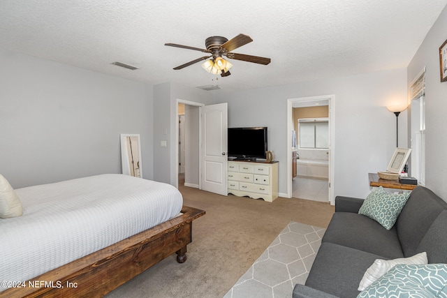 bedroom featuring ensuite bath, ceiling fan, light colored carpet, and a textured ceiling