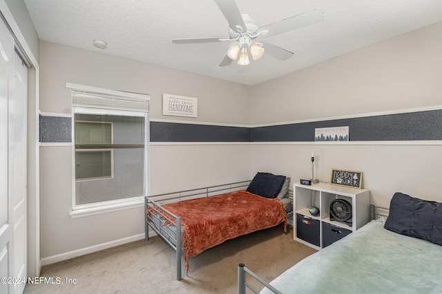 bedroom featuring a textured ceiling, carpet, ceiling fan, and a closet