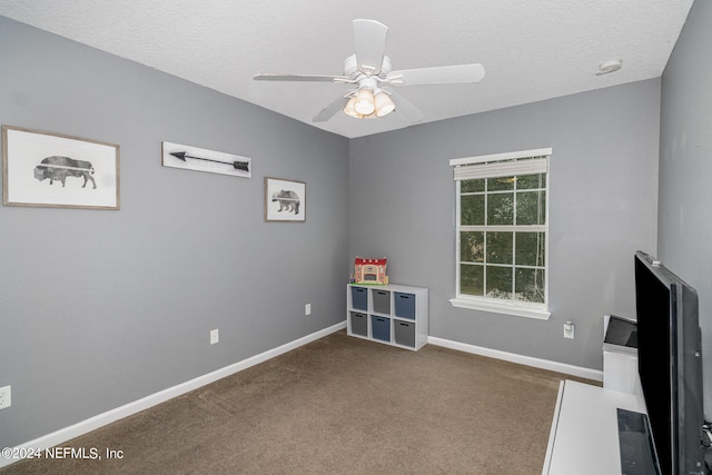 interior space featuring a textured ceiling, dark colored carpet, and ceiling fan