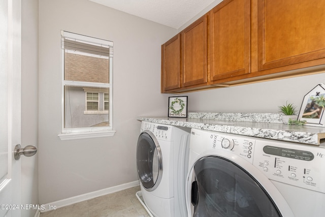 laundry room with a textured ceiling, light tile patterned floors, independent washer and dryer, and cabinets