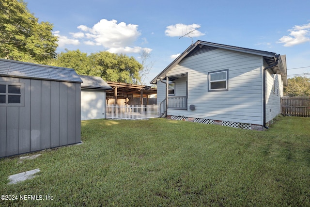 rear view of house featuring a lawn and a storage shed