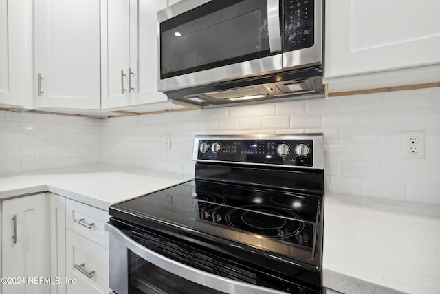 kitchen featuring black / electric stove, backsplash, and white cabinetry