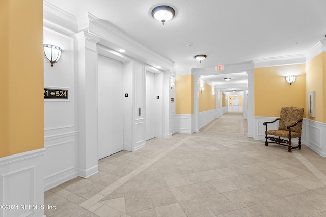 hallway featuring decorative columns, elevator, crown molding, and light tile patterned flooring