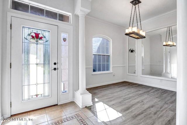 entryway with ornamental molding, decorative columns, and light hardwood / wood-style flooring