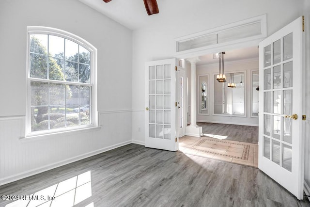 unfurnished dining area featuring french doors, a healthy amount of sunlight, decorative columns, and hardwood / wood-style floors