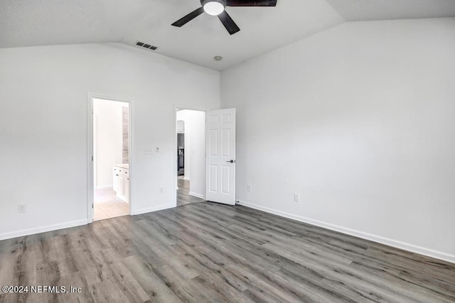 unfurnished bedroom with hardwood / wood-style floors, connected bathroom, vaulted ceiling, and ceiling fan