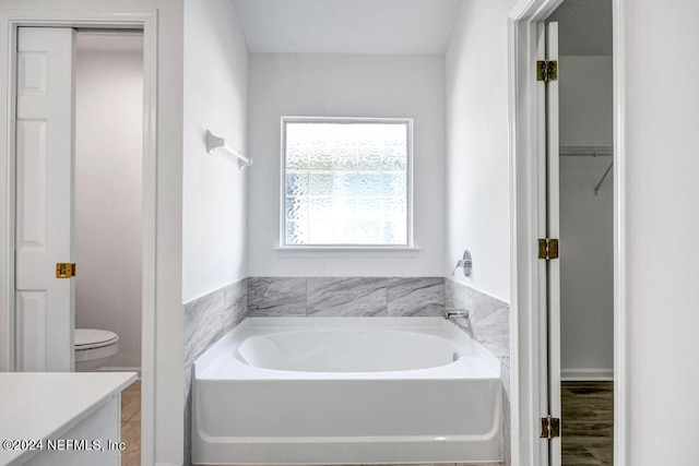 bathroom with toilet, a tub to relax in, vanity, and hardwood / wood-style floors