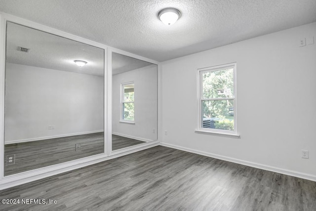 unfurnished room featuring a textured ceiling, dark hardwood / wood-style flooring, and a wealth of natural light