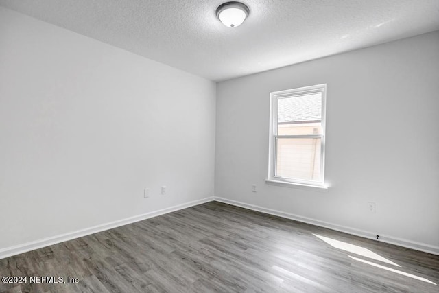 spare room with a textured ceiling and dark wood-type flooring