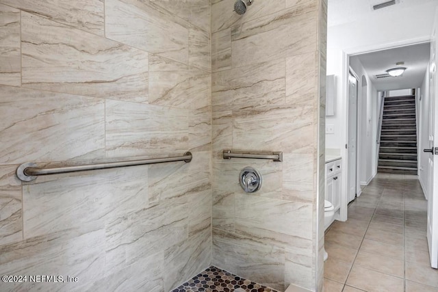 bathroom featuring vanity, toilet, tiled shower, and tile patterned flooring