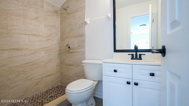 bathroom featuring vanity, a tile shower, and toilet