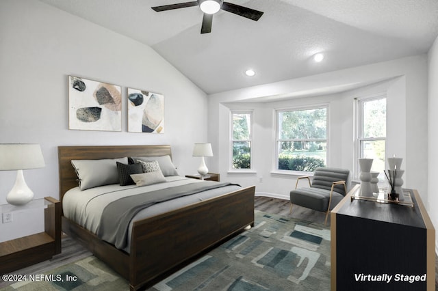 bedroom with lofted ceiling, dark hardwood / wood-style floors, a textured ceiling, and ceiling fan