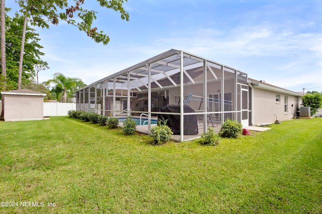 back of property featuring cooling unit, a fenced in pool, a yard, and a lanai