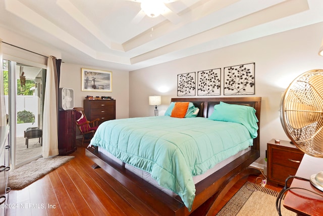 bedroom with wood-type flooring, a tray ceiling, and ceiling fan