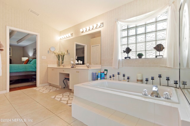 bathroom with a relaxing tiled tub, tile patterned floors, and vanity