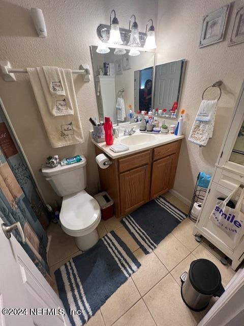 bathroom with tile patterned flooring, walk in shower, vanity, and toilet