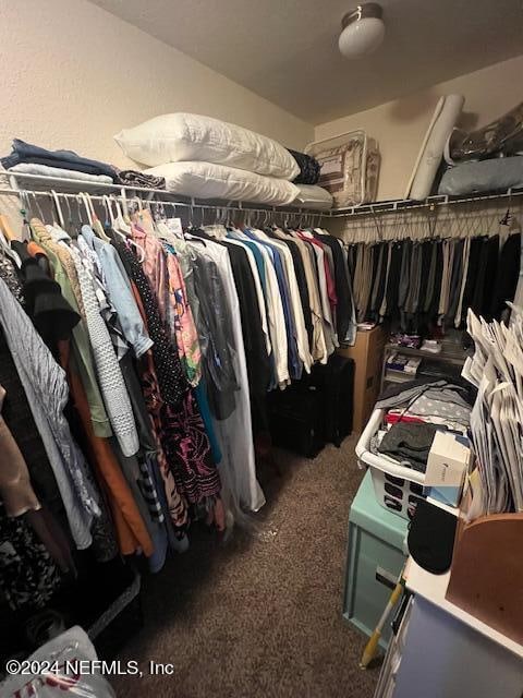 walk in closet featuring dark colored carpet