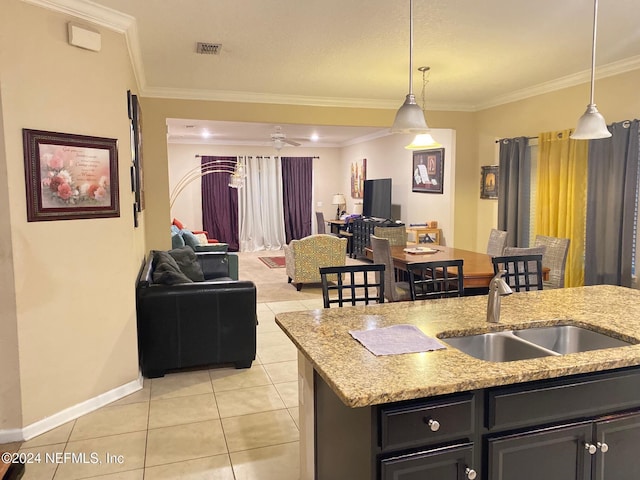 kitchen featuring sink, an island with sink, pendant lighting, and ornamental molding