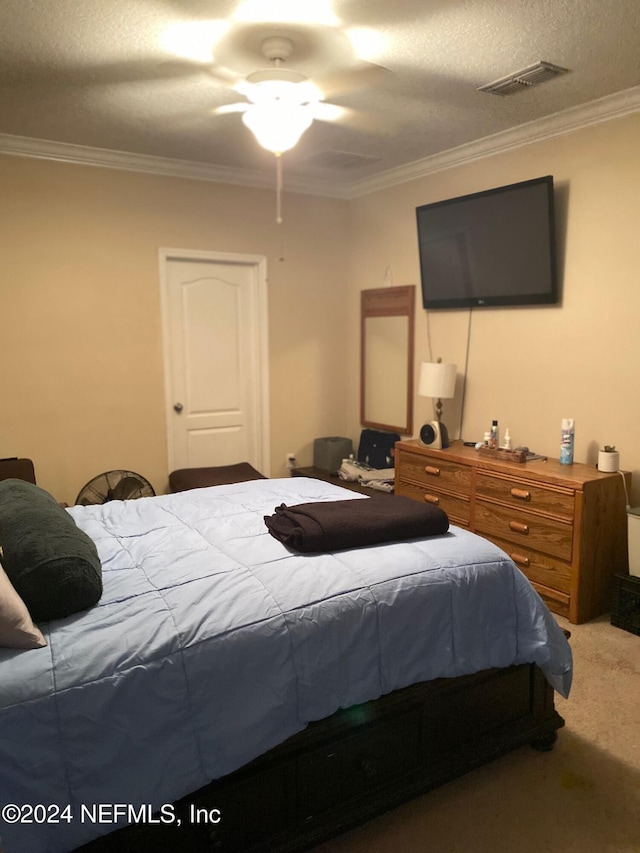 carpeted bedroom with a textured ceiling, ceiling fan, and crown molding