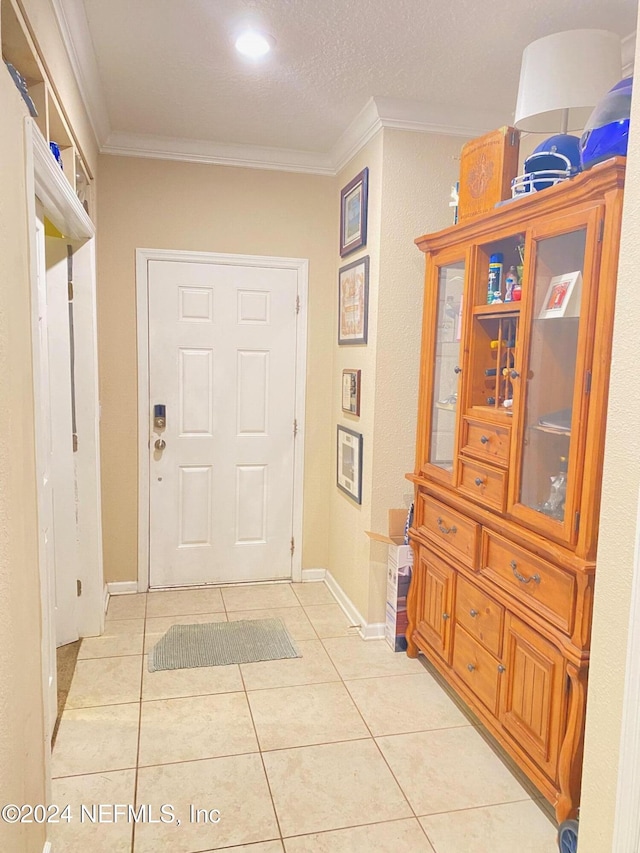 interior space with light tile patterned floors, a textured ceiling, and ornamental molding