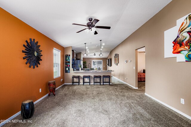 carpeted living room featuring vaulted ceiling and ceiling fan