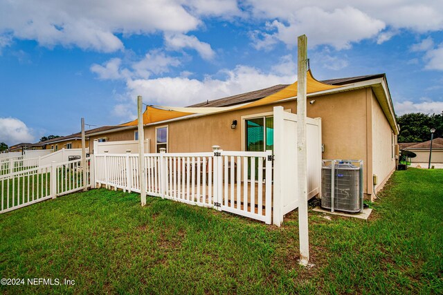 back of house with a yard and central air condition unit