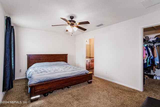 carpeted bedroom with connected bathroom, a closet, a textured ceiling, ceiling fan, and a walk in closet