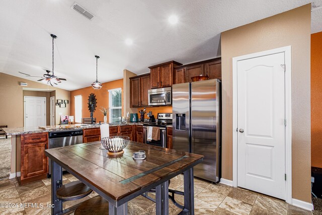 kitchen featuring kitchen peninsula, light stone countertops, pendant lighting, stainless steel appliances, and ceiling fan