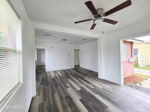 unfurnished living room featuring dark wood-type flooring and ceiling fan