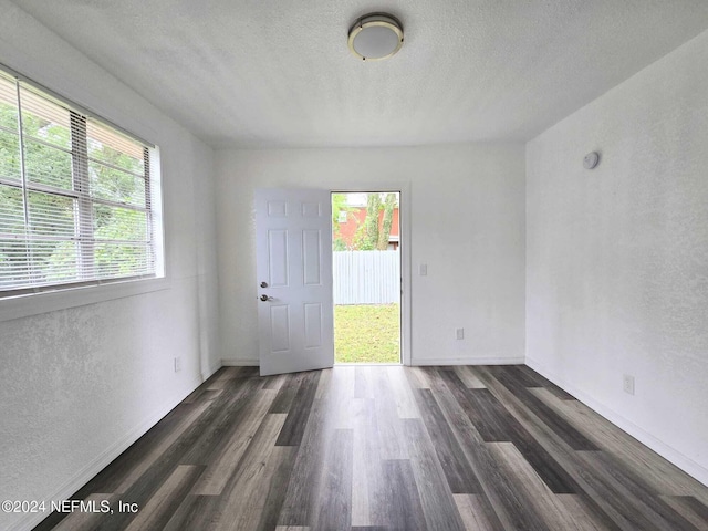 spare room with a textured ceiling and dark hardwood / wood-style flooring