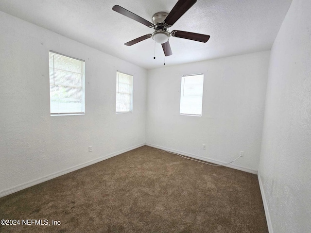 carpeted spare room featuring ceiling fan and a textured ceiling