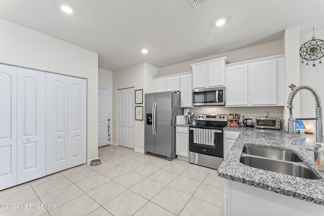 kitchen with sink, white cabinetry, appliances with stainless steel finishes, light tile patterned floors, and light stone countertops