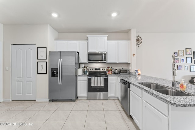 kitchen featuring light stone countertops, stainless steel appliances, white cabinets, and kitchen peninsula