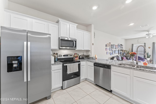 kitchen featuring ceiling fan, white cabinets, sink, stainless steel appliances, and light stone countertops