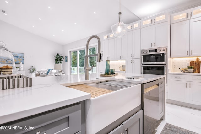 kitchen featuring decorative backsplash, white cabinetry, vaulted ceiling, stainless steel appliances, and decorative light fixtures