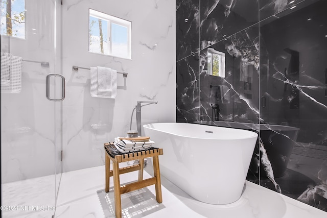 bathroom featuring shower with separate bathtub, tile walls, and a wealth of natural light