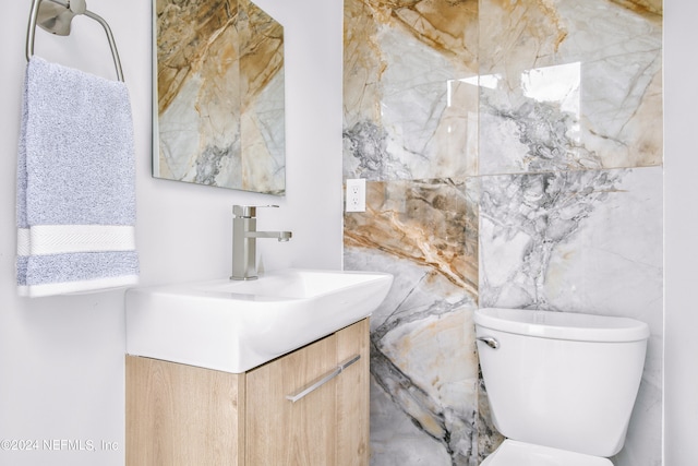 bathroom featuring tile walls, vanity, and toilet