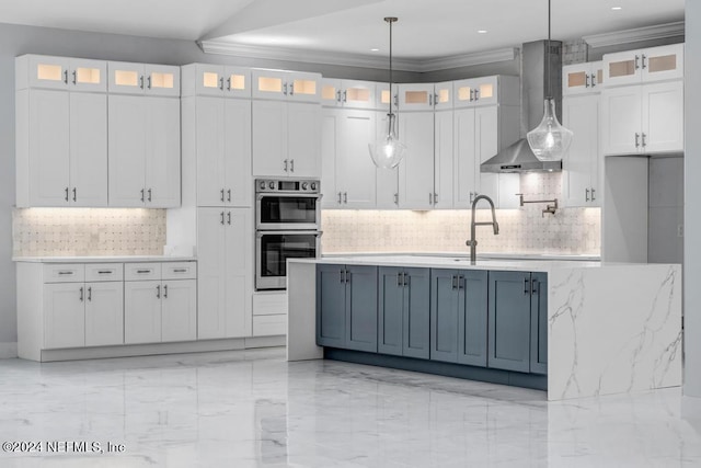 kitchen featuring hanging light fixtures, wall chimney range hood, light stone counters, and white cabinets