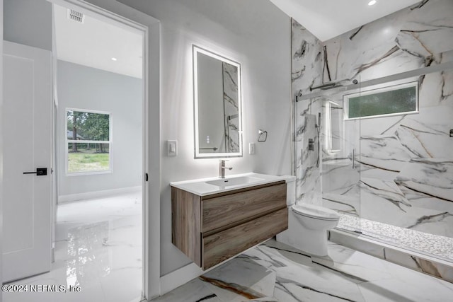 bathroom featuring a tile shower, vanity, and toilet