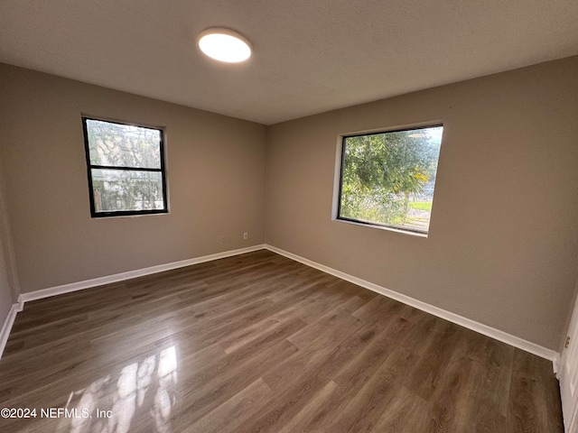 empty room with a healthy amount of sunlight and dark hardwood / wood-style flooring