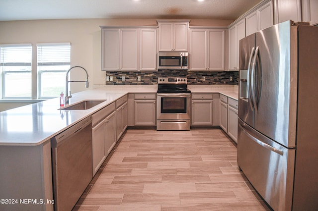 kitchen with light wood-type flooring, gray cabinets, sink, and stainless steel appliances