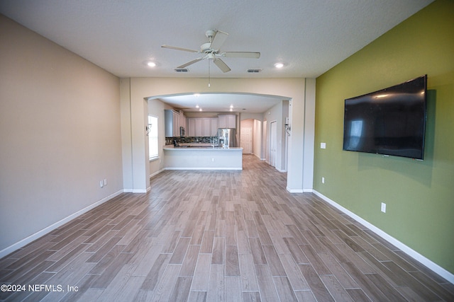 unfurnished living room featuring light wood-type flooring and ceiling fan