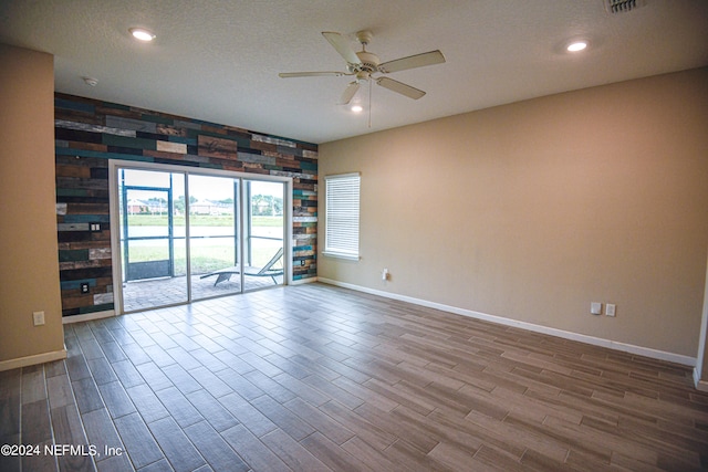 empty room featuring a textured ceiling, wood-type flooring, and ceiling fan