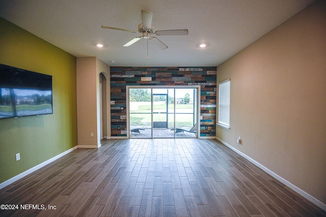 unfurnished living room featuring ceiling fan and dark wood-type flooring