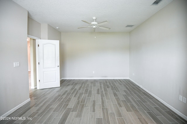 empty room with a textured ceiling, dark wood-type flooring, and ceiling fan