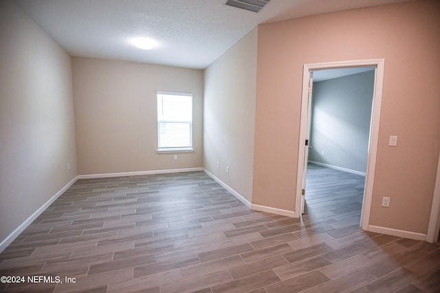 spare room with a textured ceiling and hardwood / wood-style flooring