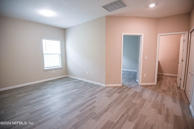 unfurnished room featuring hardwood / wood-style flooring and a textured ceiling